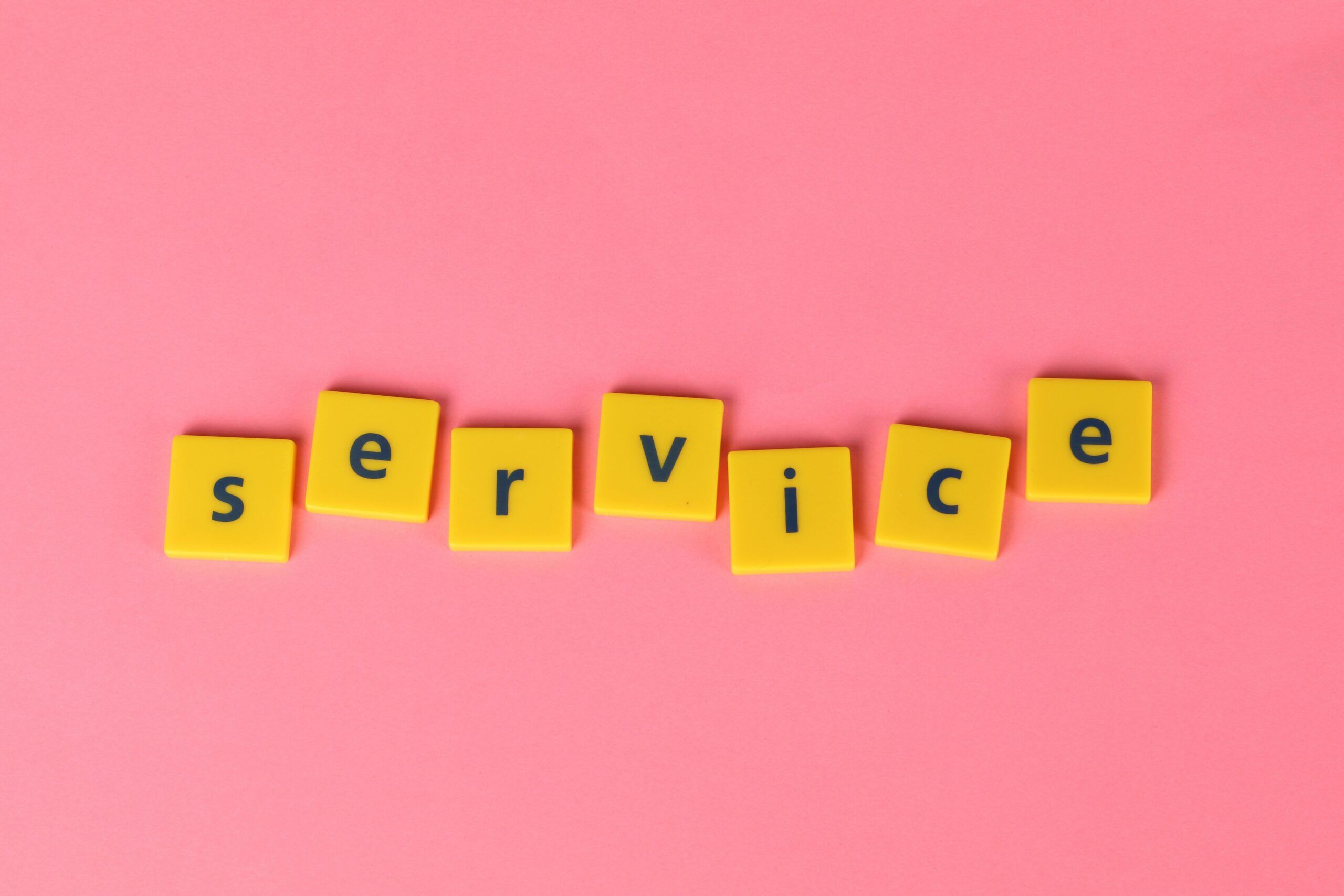 Yellow tiles spelling the word 'service' on a pink background, visually appealing design.